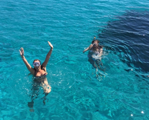 Ospiti si rilassano prendendo il sole a bordo della barca a vela all'Asinara.